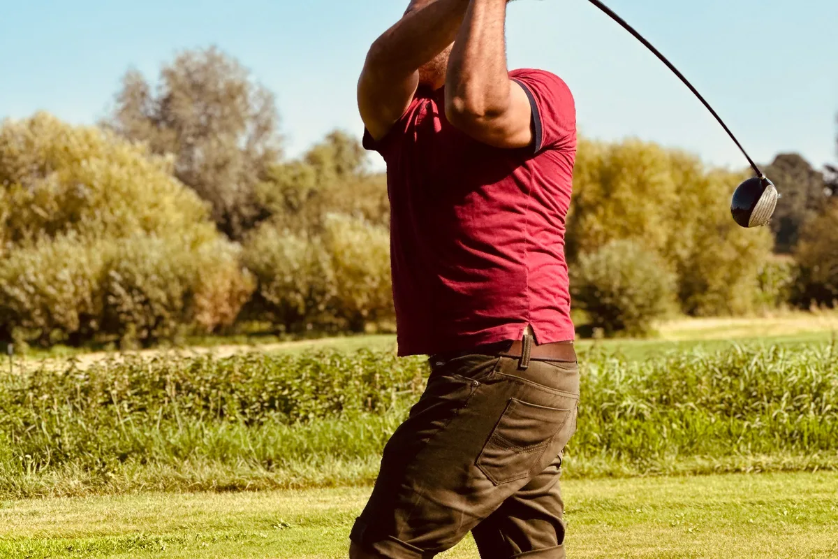Golfer mid swing on a course